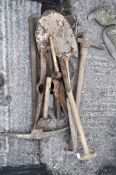A collection of vintage tools including pick axes, shovel, spade,