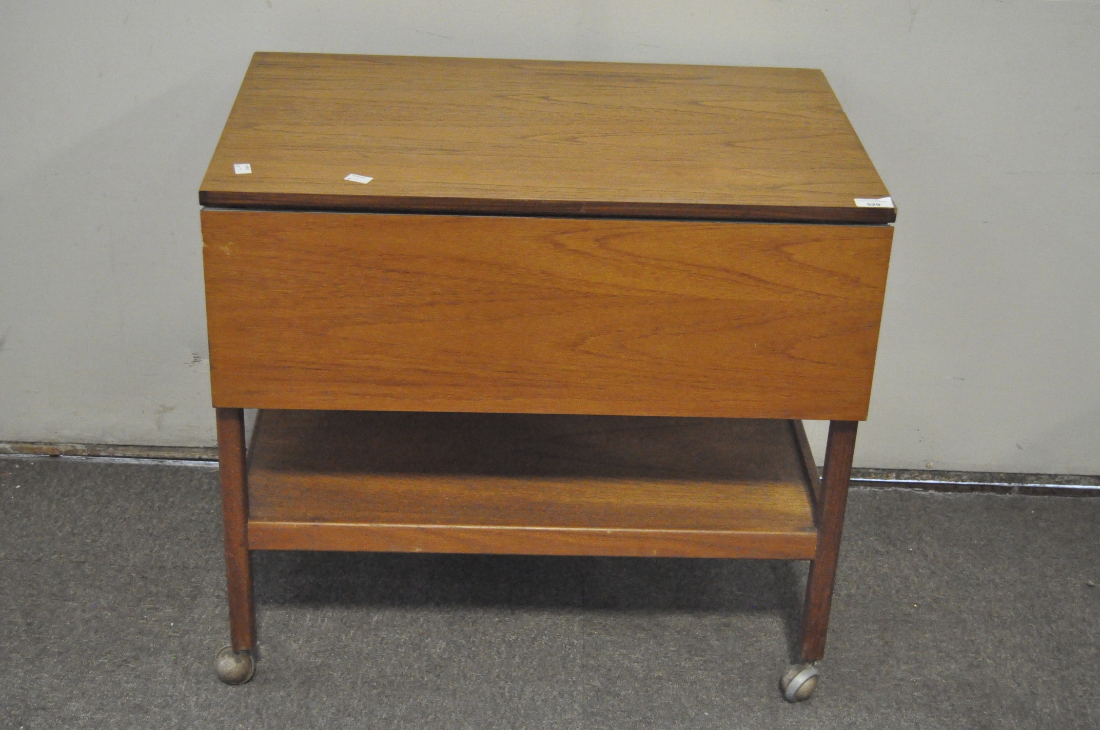 A vintage mid-century drop leaf trolley table, raised upon original castors,