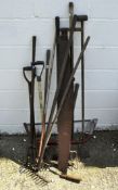 A collection of carpentry and gardening tools including a rake, forks,