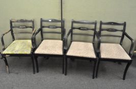 A set of four armchairs, painted black, with remains of colourful floral details,