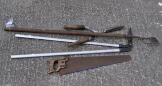 A quantity of tools including a hoe and a saw