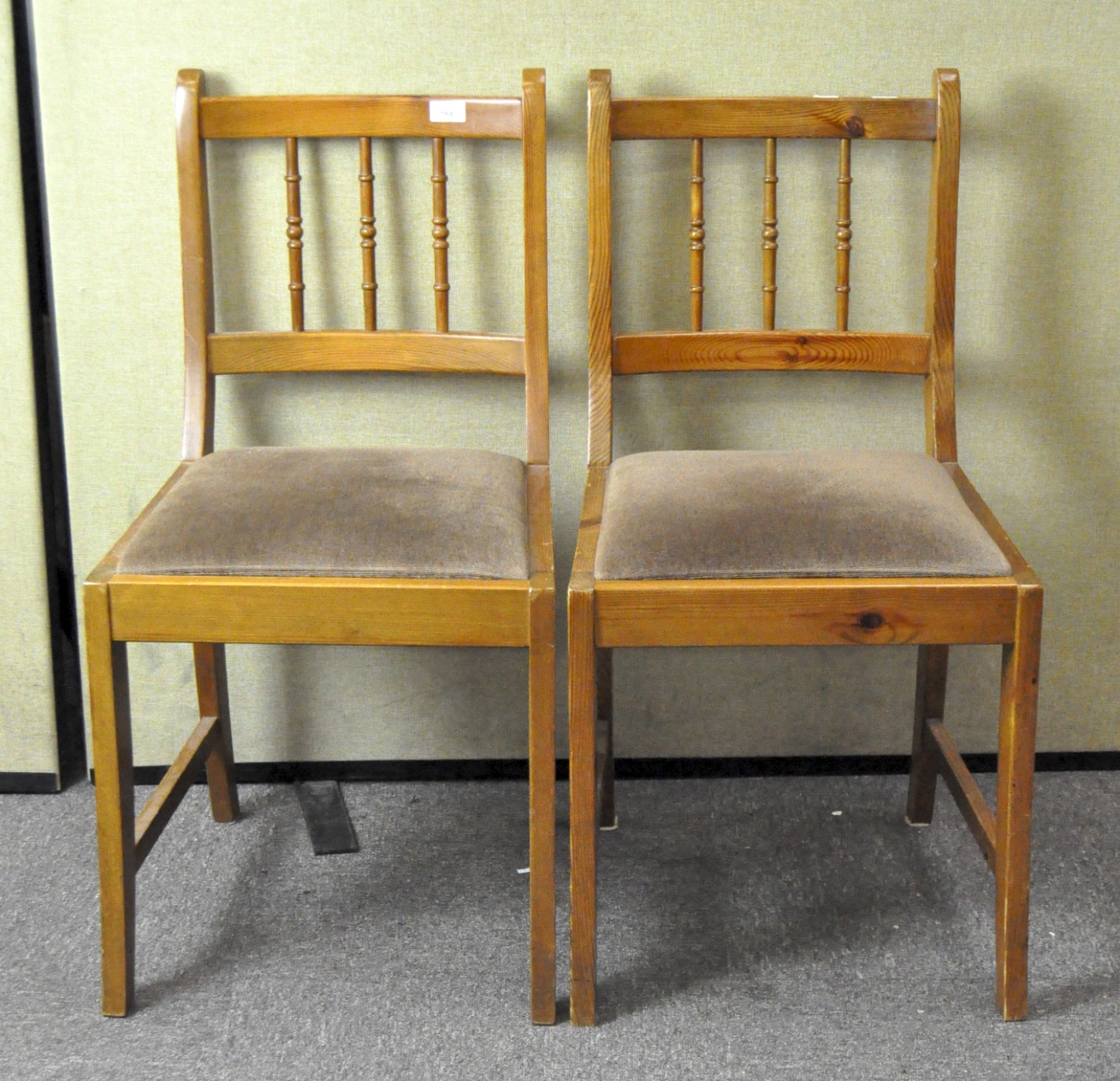 A pair of contemporary dining chairs, with spindle backs and upholstered in brown fabric,