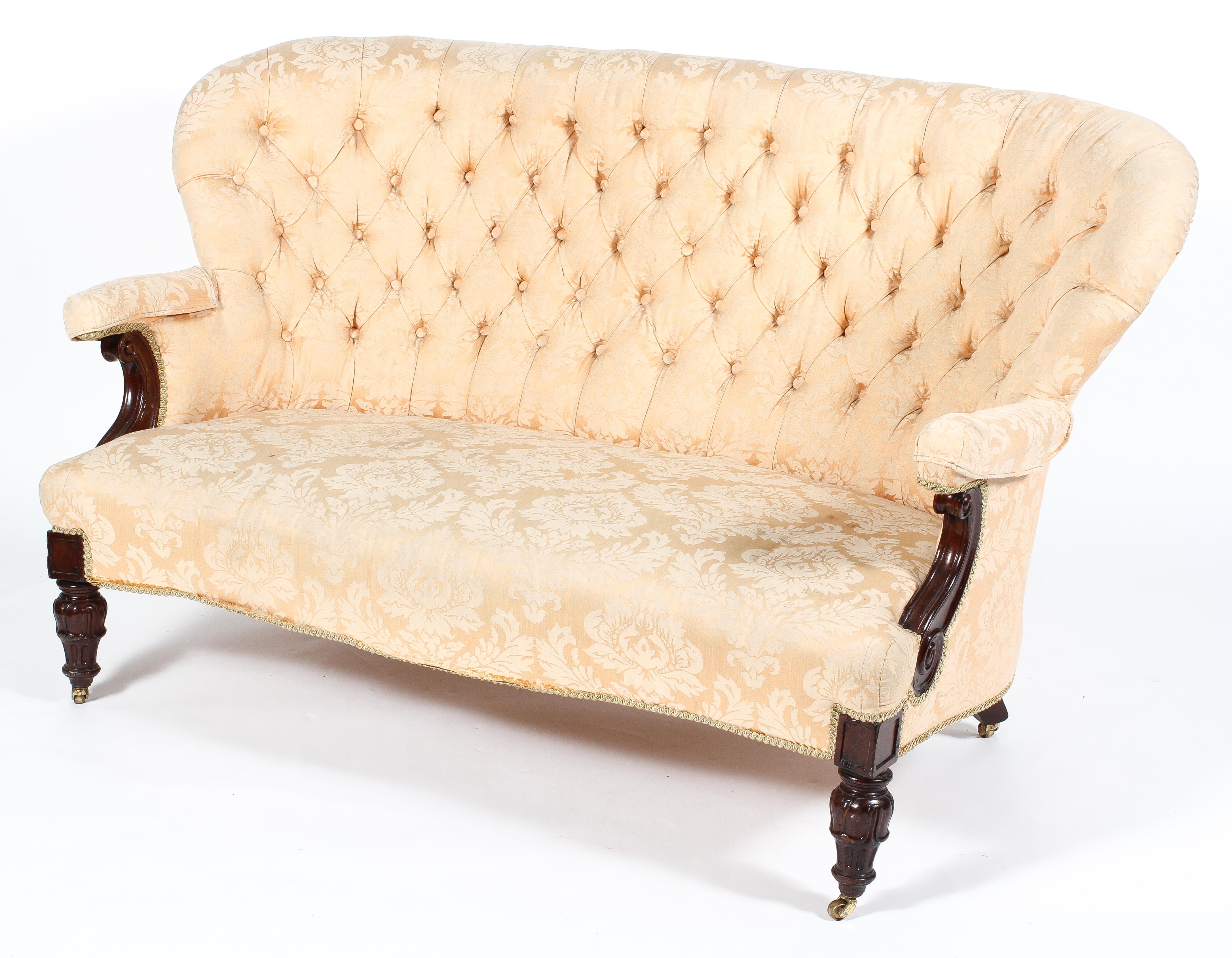 A Victorian button back settee, of serpentine form with scroll carved arms and foliate carved legs,