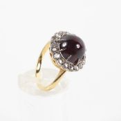 A yellow and white metal cluster ring principally set with a round cabochon cut garnet