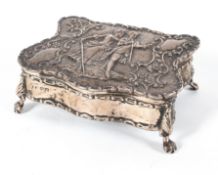 An Edwardian silver jewellery casket, of serpentine form, a scene of a couple in relief,