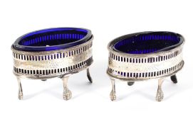 A pair of George III oval footed silver salts with blue glass liners, hallmarked London 1786,