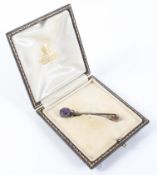 A yellow metal safety pin brooch principally set with an oval faceted amethyst