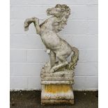 Garden Statuary: a cast stone figure of a rearing horse, on a stepped plinth with foliate corners,