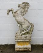 Garden Statuary: a cast stone figure of a rearing horse, on a stepped plinth with foliate corners,