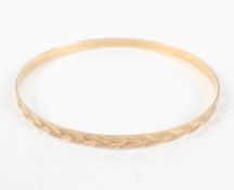 A yellow metal full bangle with engraved design. Hallmarked 9ct gold, London, 1990.