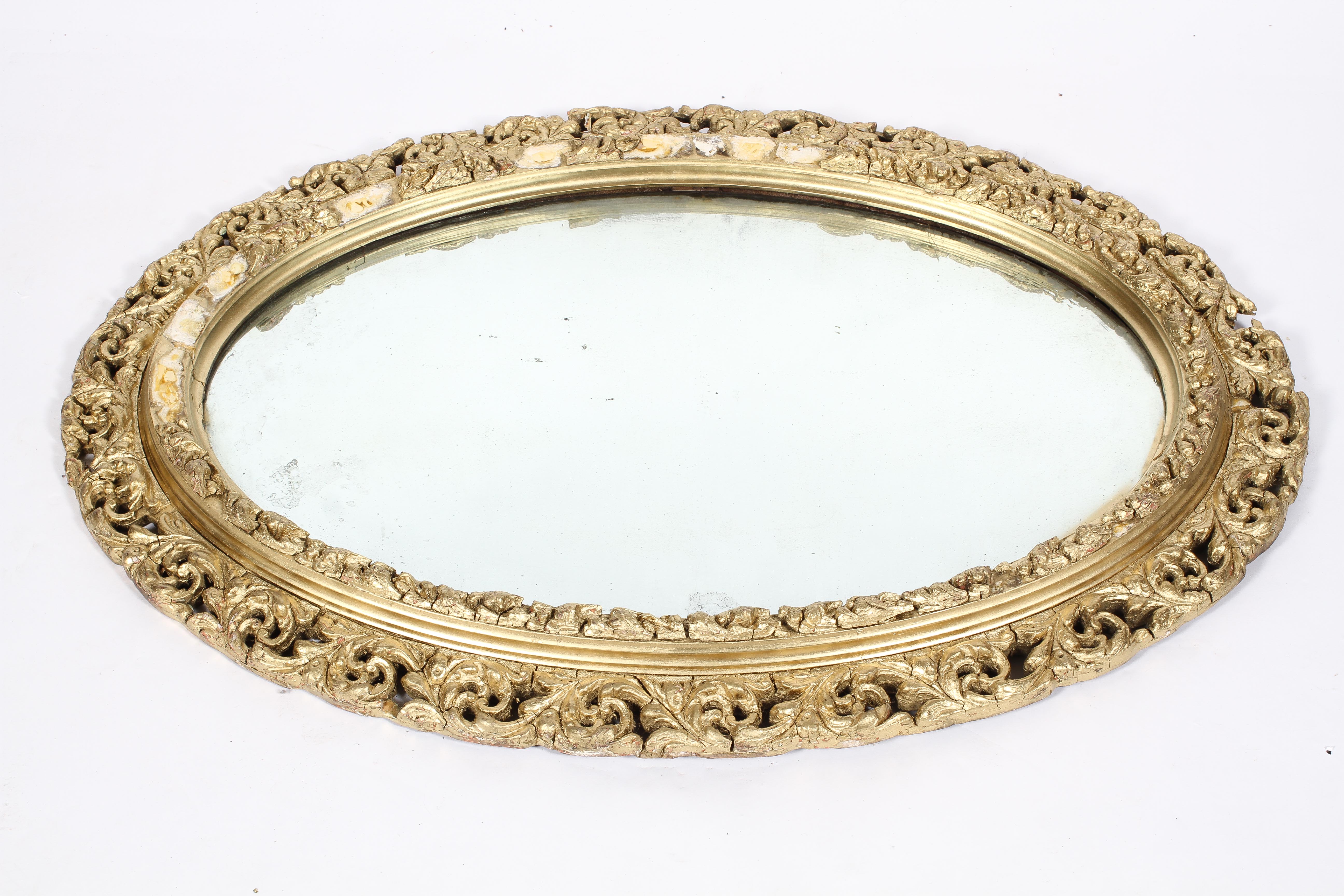 A Victorian gilt framed oval mirror, the plate inside a pierced, scrolling frame,