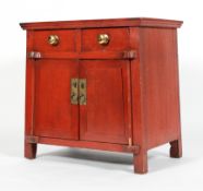 An Chinese red painted hardwood cabinet, with two drawers above two cupboard doors,