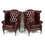 A pair of leather button wingback armchairs,