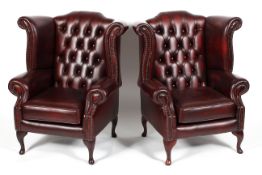 A pair of leather button wingback armchairs,