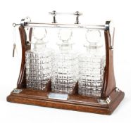 An oak and silver plate mounted three bottle tantalus, with square section,