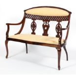 An Edwardian mahogany two seater salon settee, with foliate carved back with pierced trellis,