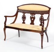 An Edwardian mahogany two seater salon settee, with foliate carved back with pierced trellis,