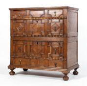 A Carolean style oak chest of drawers, the front moulded with geometric panels,