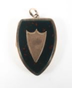 A yellow metal shield shape locket pendant.