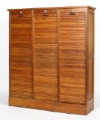 An oak mid-century three section tambour filing cabinet, enclosing adjustable shelves,