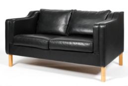 A late 20th century Danish-style black leather two seater sofa, with drop-in cushions and arm rests,