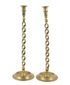 A pair of brass candlesticks, the ringed sconces on a double spiral column and circular foot,