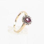 A yellow metal cluster ring principally set with an oval faceted ruby