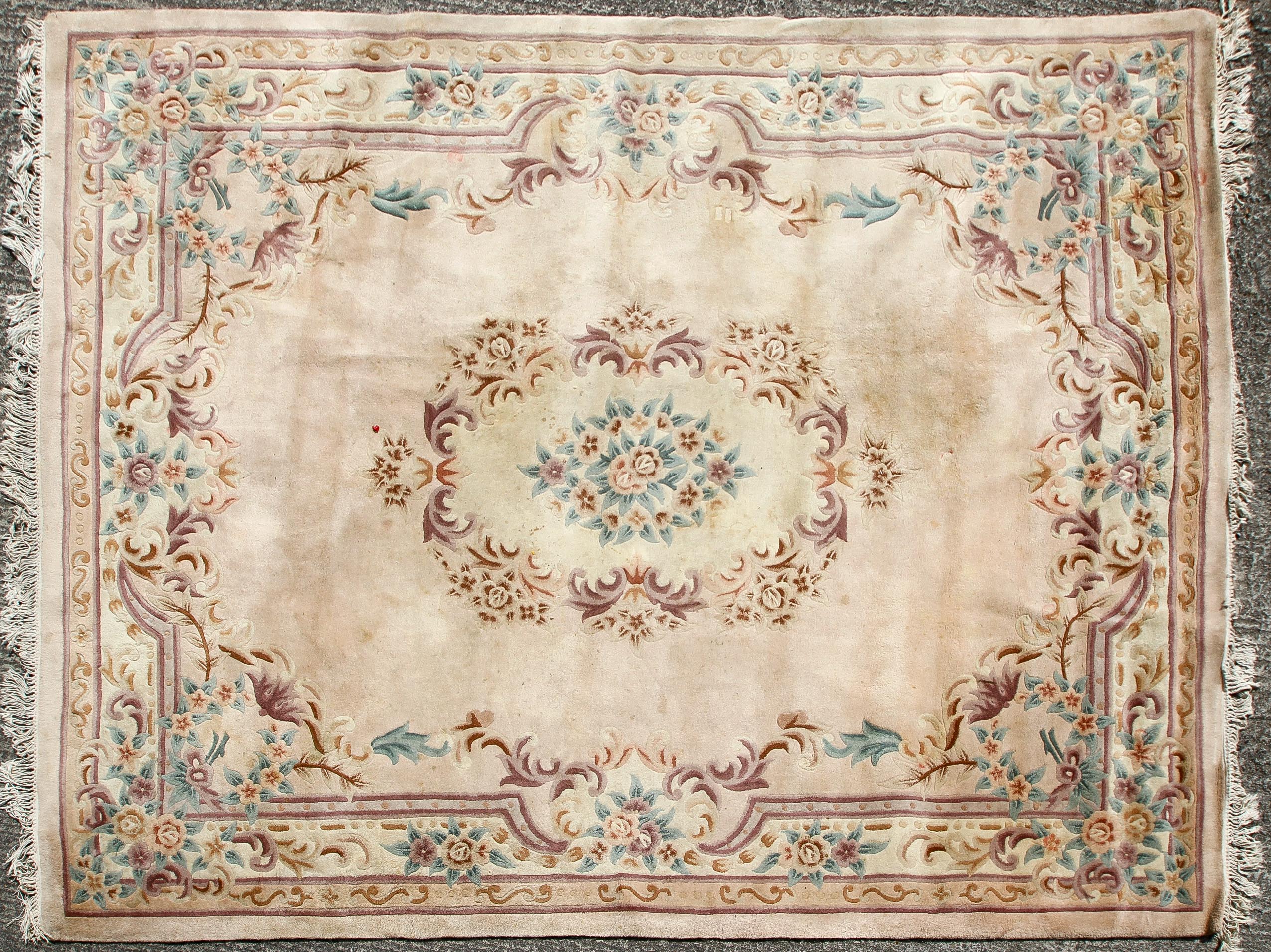 A large 20th century rug, decorated with floral motifs and a central medallion on a cream ground,