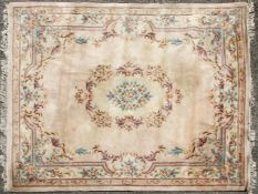 A large 20th century rug, decorated with floral motifs and a central medallion on a cream ground,