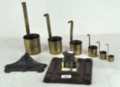Two early 20th century inkwells and a set of brass measuring jugs,