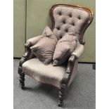 A Victorian mahogany button back armchair with scrolled arms, on turned legs with casters,