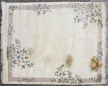 A large 20th century rug, decorated with pink and green flowers on a cream ground,