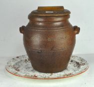 A large stoneware pot and wooden cover,
