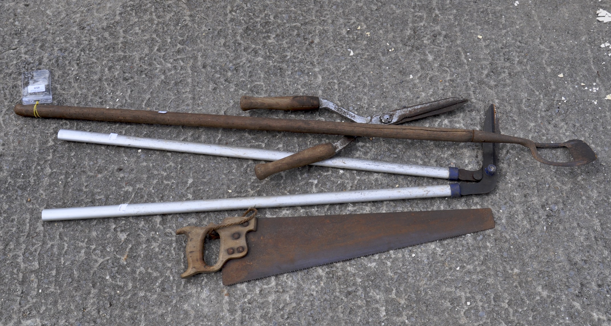 A quantity of tools including a hoe, a saw,