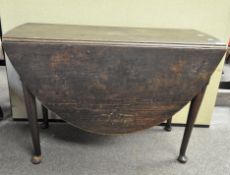 A 19th century oval oak drop leaf dining table on tapered legs and bun feet, height 71 cm,