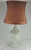 A white ceramic table lamp with floral decoration and a pink shade,
