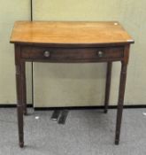 A Victorian mahogany side table with bow front and single drawer, on turned legs,