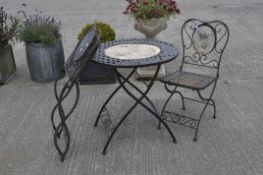 A metal table and chairs, with treliss pattern inset of fruiting vines design, the table 74 cm high,