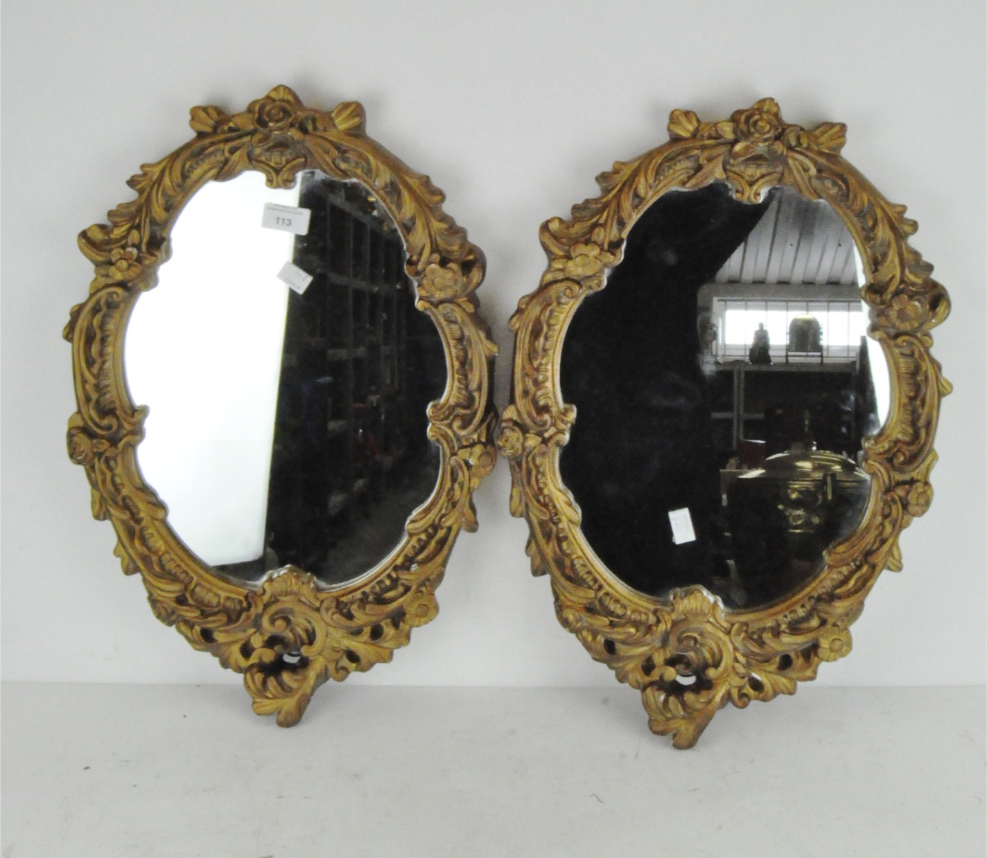 A pair of gilt gesso framed wall mirrors with carved floral and scroll decoration,