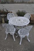 A white painted metal garden table and four chairs, pierced with palmettes,