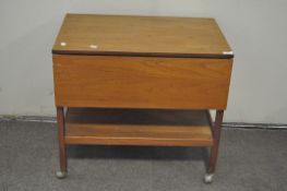 A vintage mid-century drop leaf trolley table, raised upon original castors,