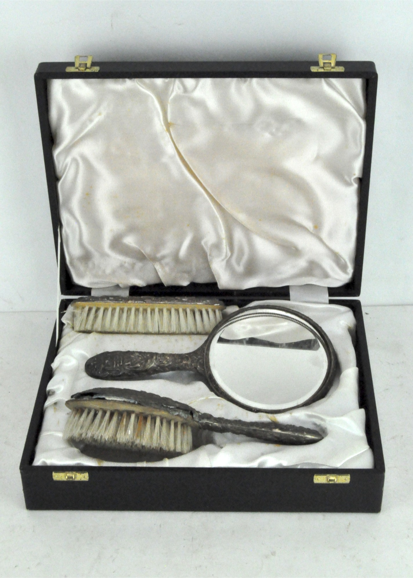 A boxed white metal dressing table set with moulded foliate decoration