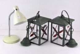 A pair of contemporary hanging lanterns featuring floral glass panels within a metal structure,