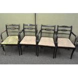 A set of four armchairs, painted black, with remains of colourful floral details,