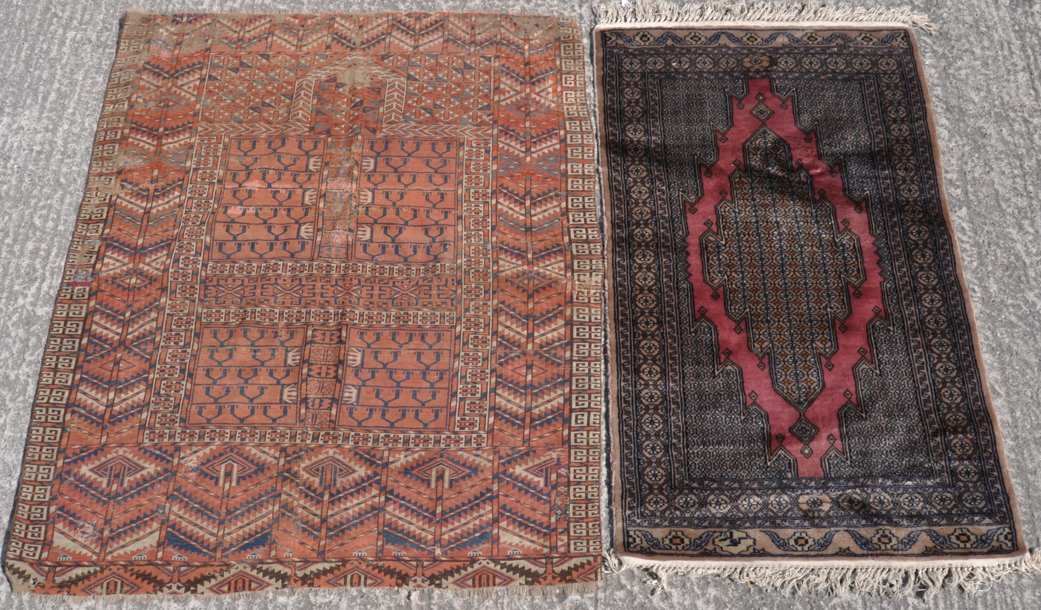 Two 20th century ground rugs, one with a cream and navy border and central motif on a red ground,