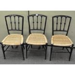 A set of three Regency style wicker seat chairs, each with three spindles with carved rosettes,