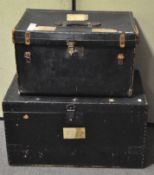 Two vintage travelling trunks, each clad in black leather, one studded with metal rivets,