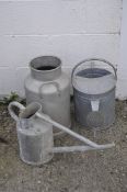 Two galvanised watering cans and a churn, the churn bearing marks for Hugonnet, Dijon,