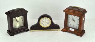 Three contemporary clocks, one by Seiko within a wooden case with a white dial with Roman numerals,