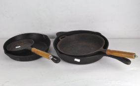 Three large skillet pans, one with a wooden handle,